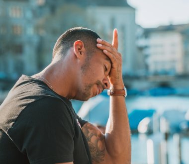 Eine Person hält sich die Hand an die Stirn, sieht nachdenklich aus.