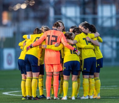 Ein Team von Fußballspieler:innen steht auf einem Feld und umarmt sich im Kreis.
