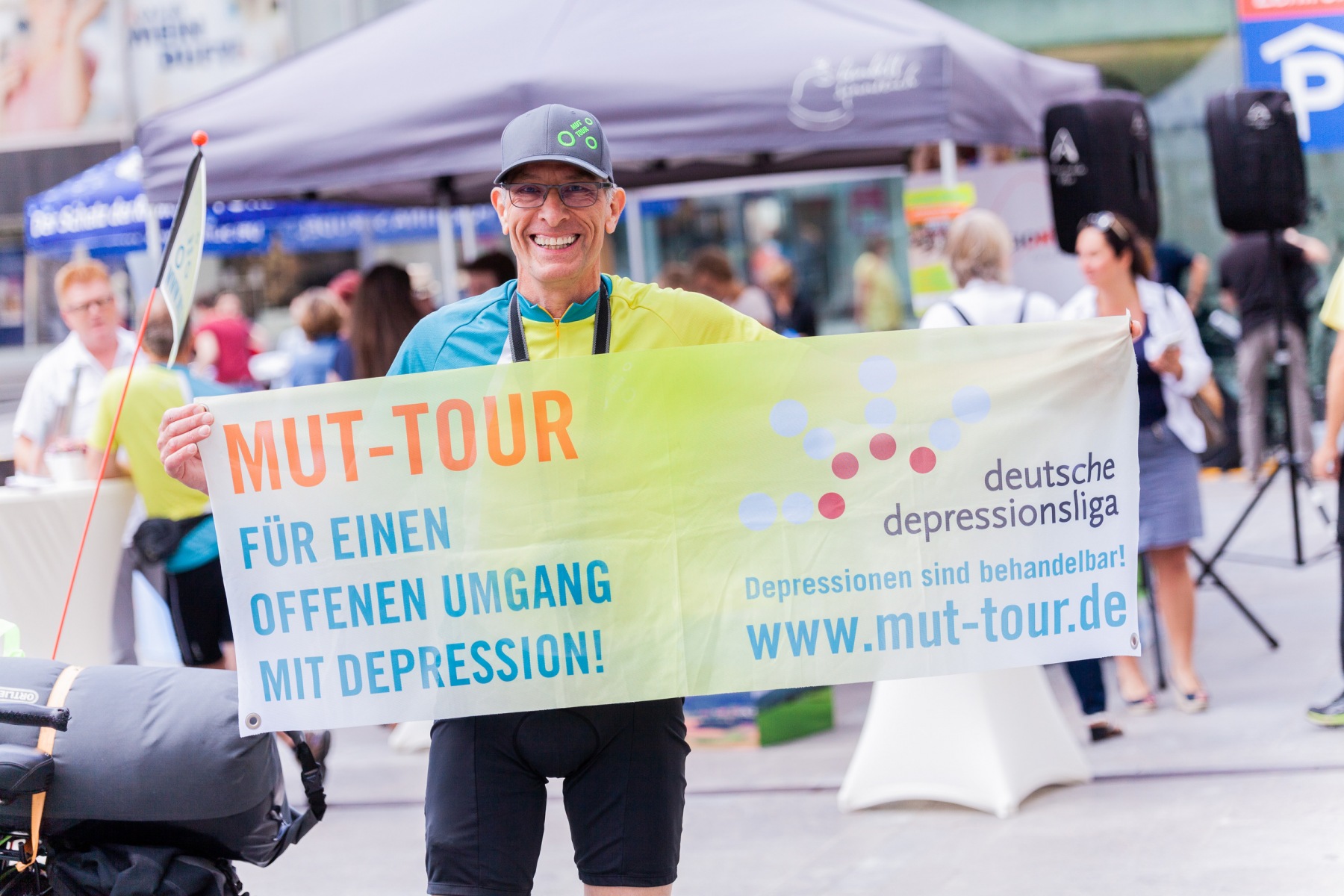 Eine Person hält ein Banner in die Kamera. Auf dem Banner steht „MUT-Tour Für einen offenen Umgang mit Depression!“